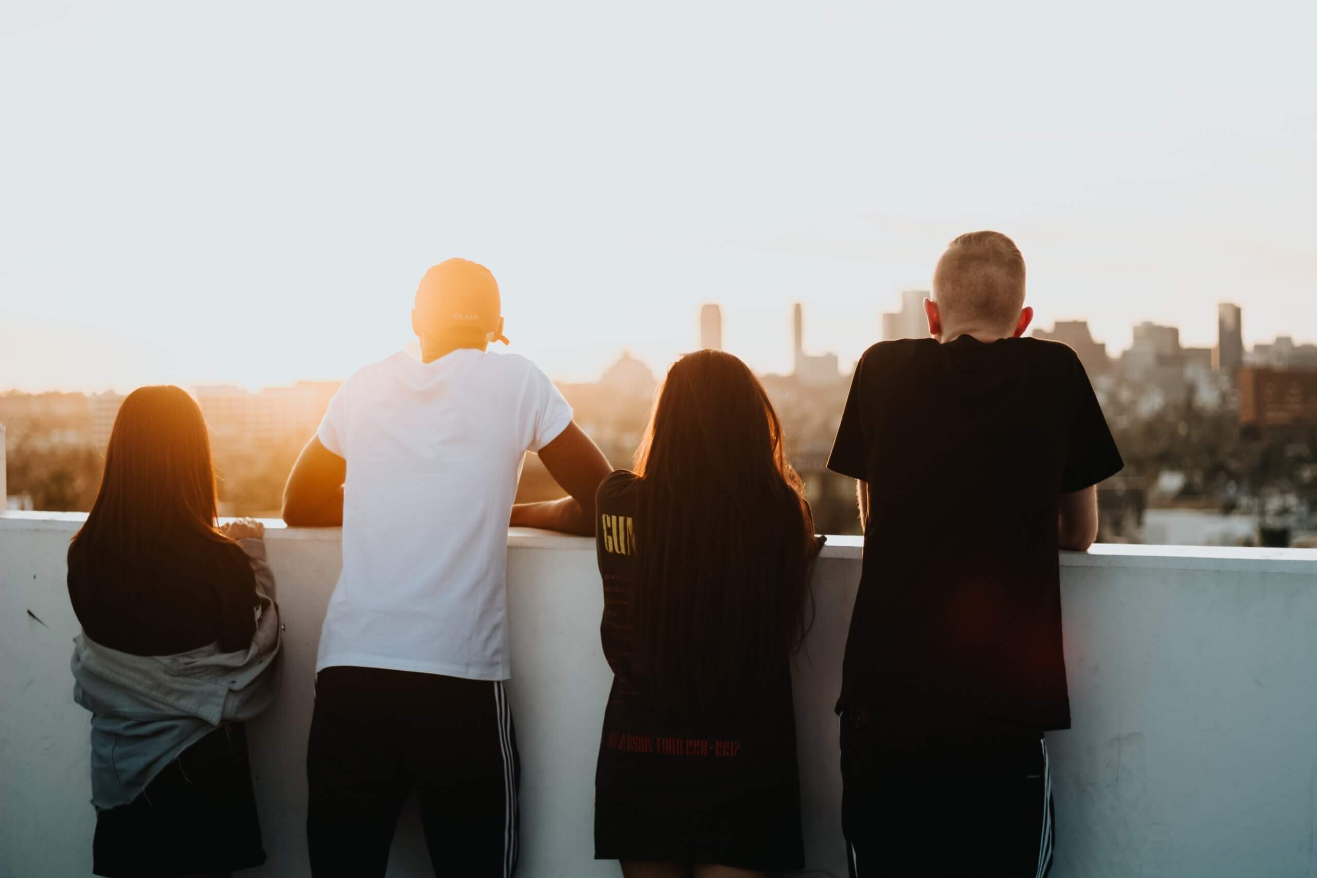 Group of 4 teens from behind on a balcony over looking the sunset